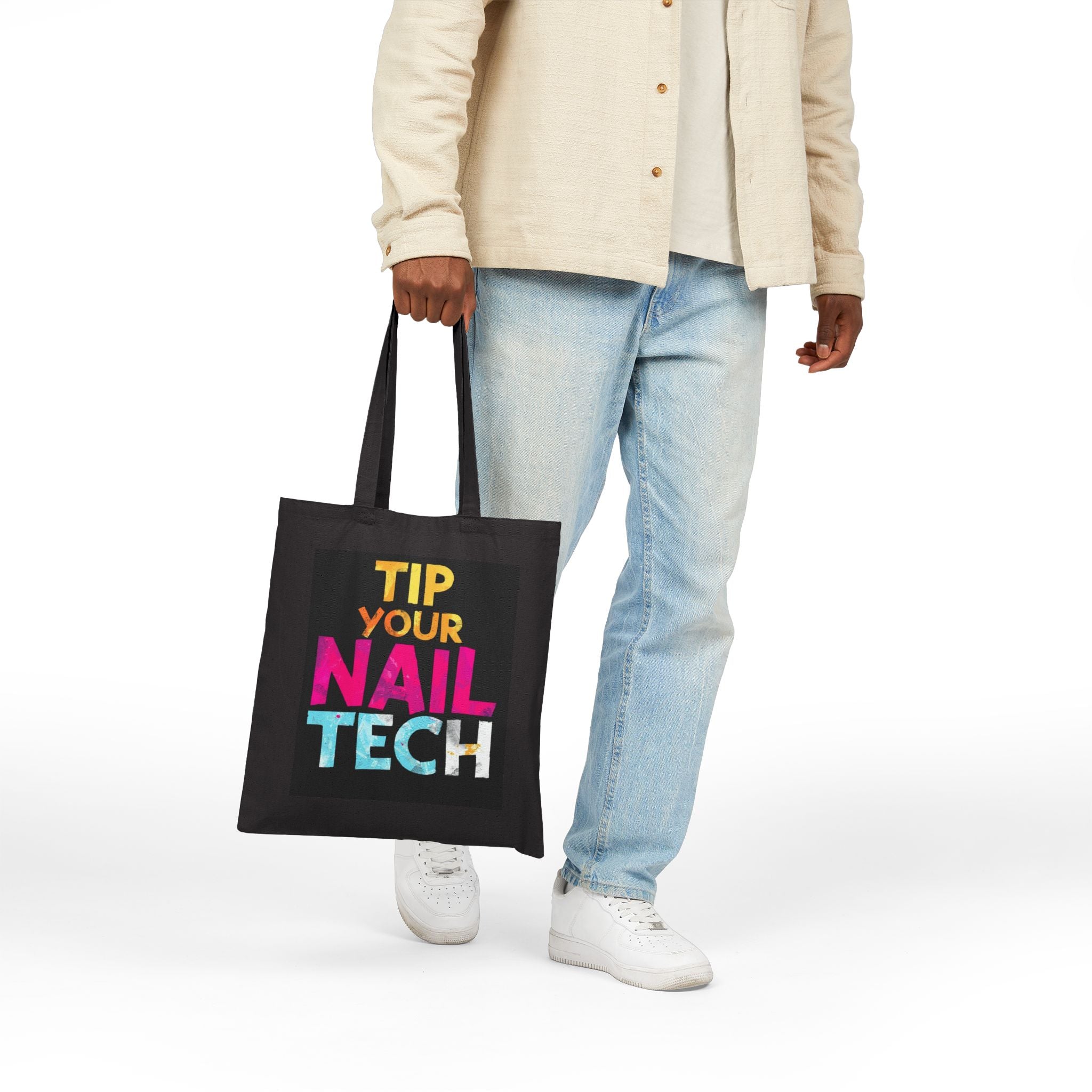 Person holding a black tote bag with colorful text on a white background