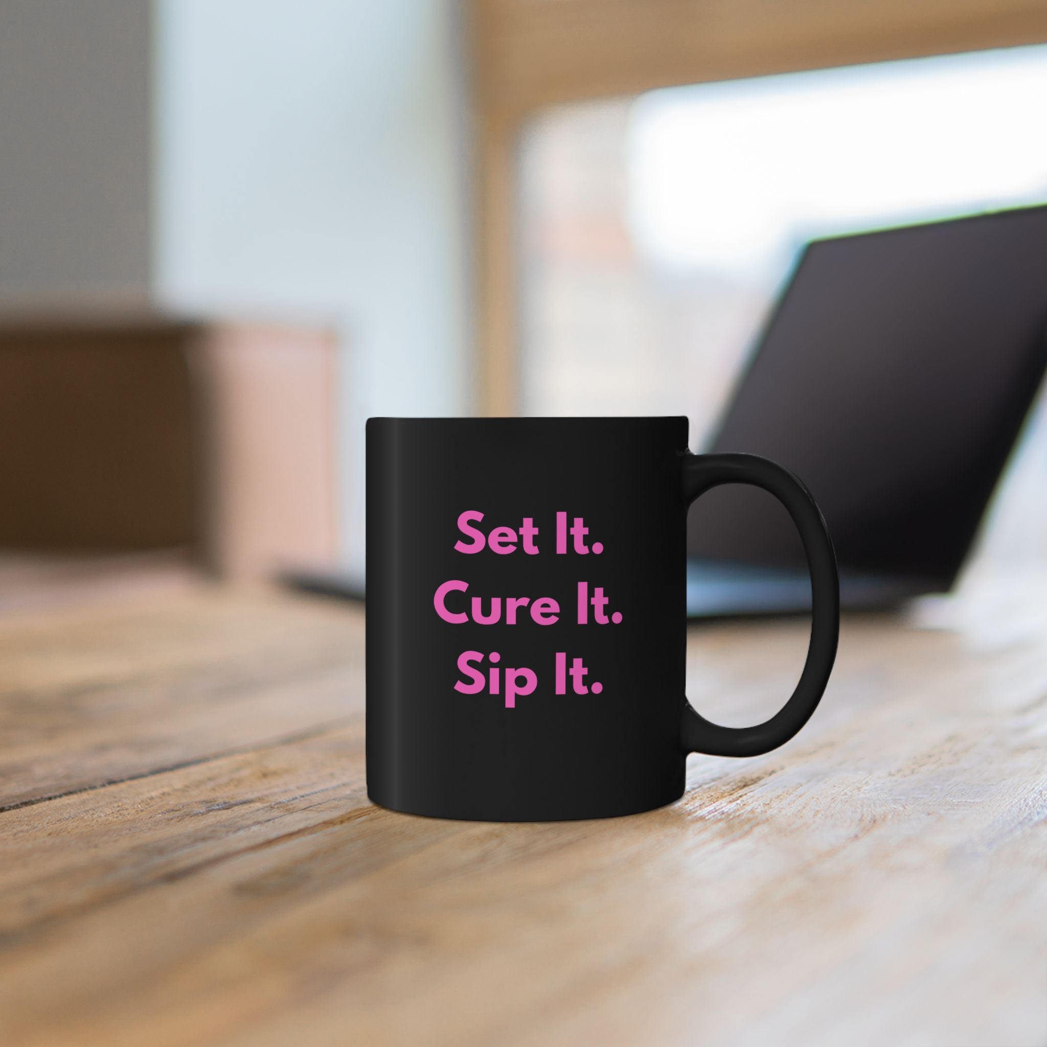 Black mug with blue text on a wooden surface