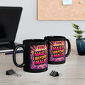 Two black mugs with colorful text design on a desk with office items.