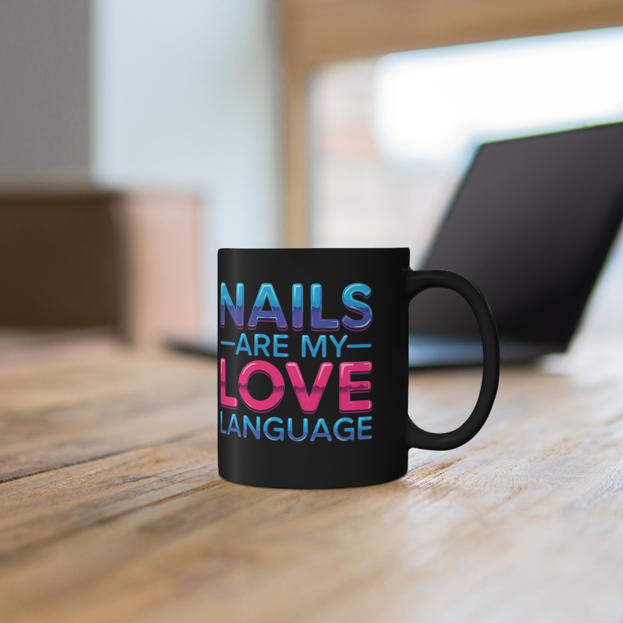 Black mug with colorful text 'NAILS ARE MY LOVE LANGUAGE' on a wooden surface.