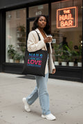 Black tote bag with colorful text 'Nails are my love language' on a white background