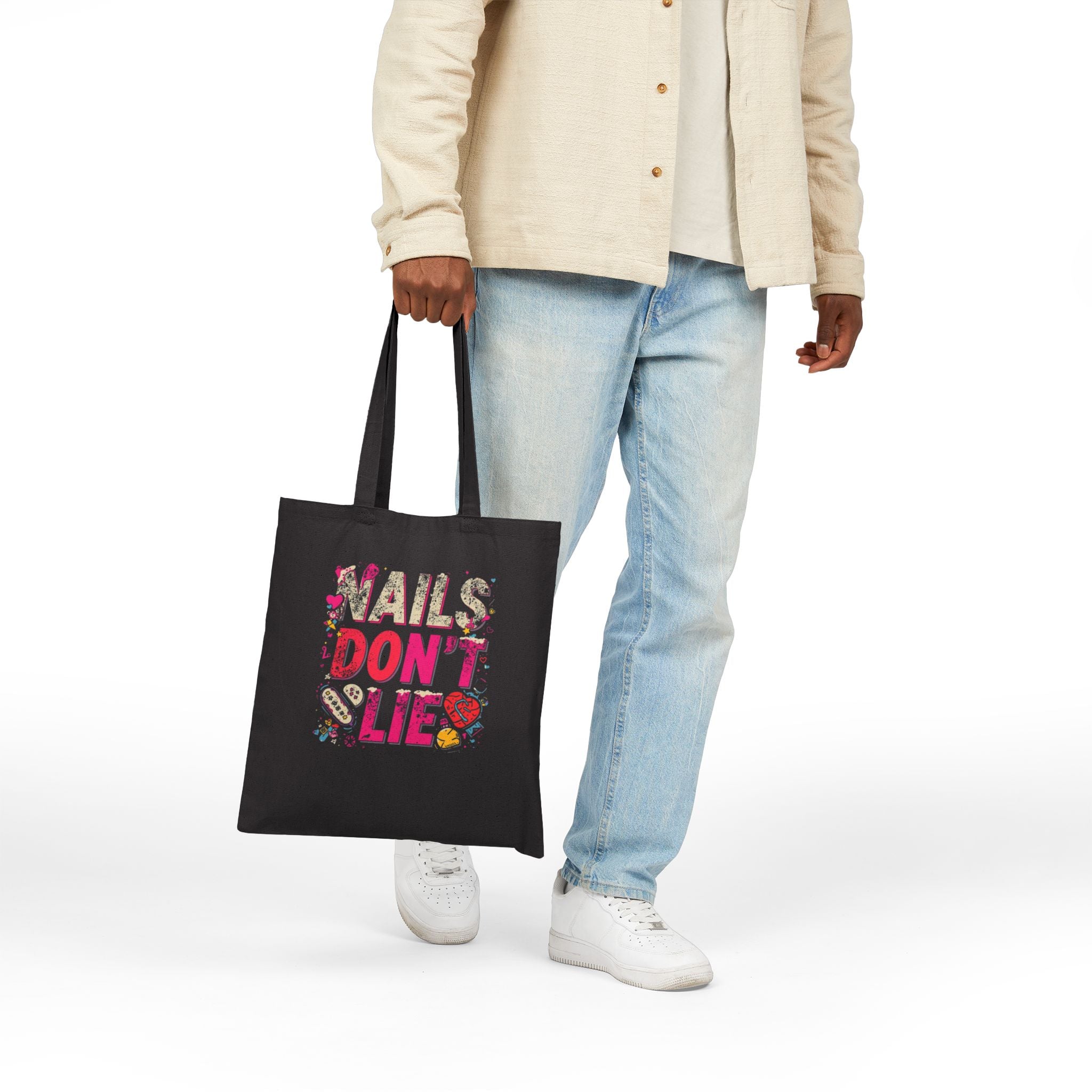 Person holding a black tote bag with a colorful truck design on a white background