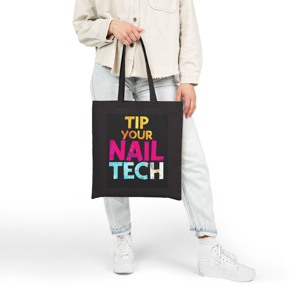 Person holding a black tote bag with colorful text on a white background
