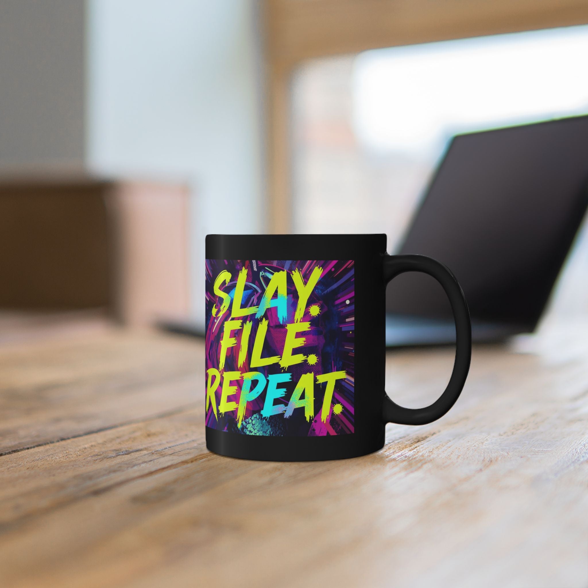 Black mug with colorful text 'Slay. File. Repeat.' on a wooden surface.