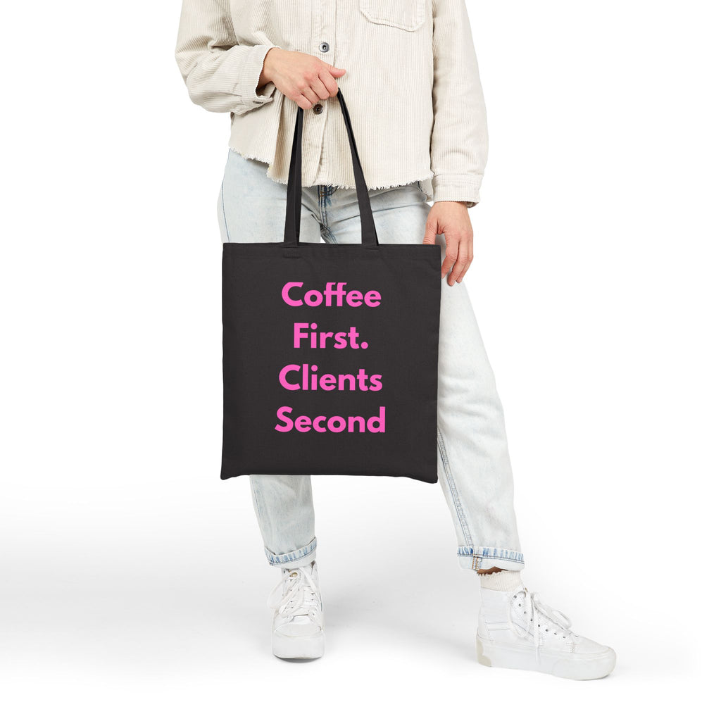 Person holding a black tote bag with pink text on a white background
