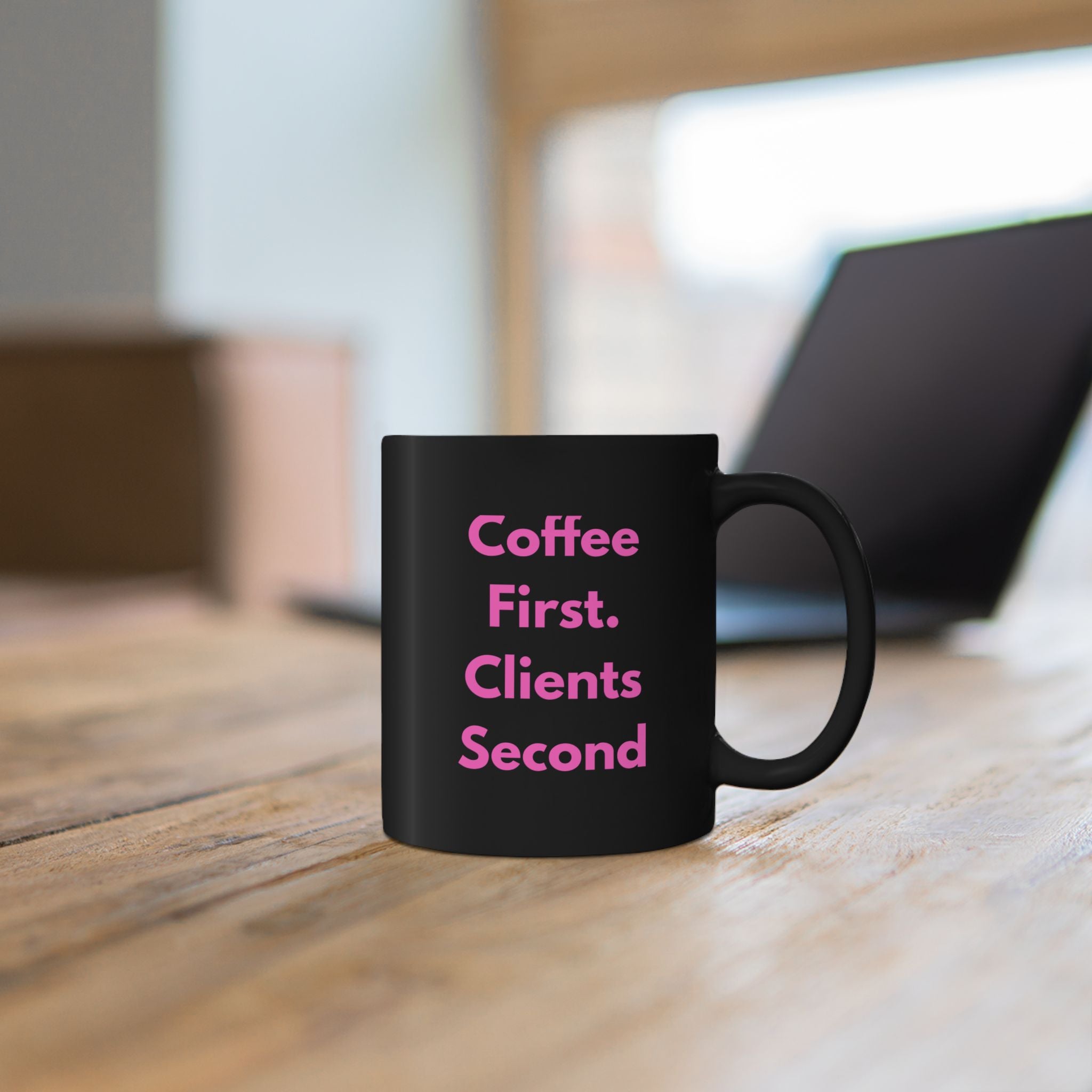 Black mug with blue text on a wooden surface